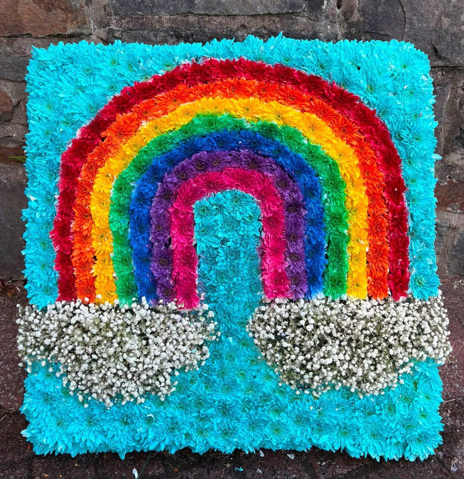 Colourful rainbow funeral tribute made with fresh flowers